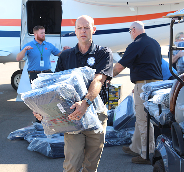 Deployed support team members unload relief items from airplane cargo door